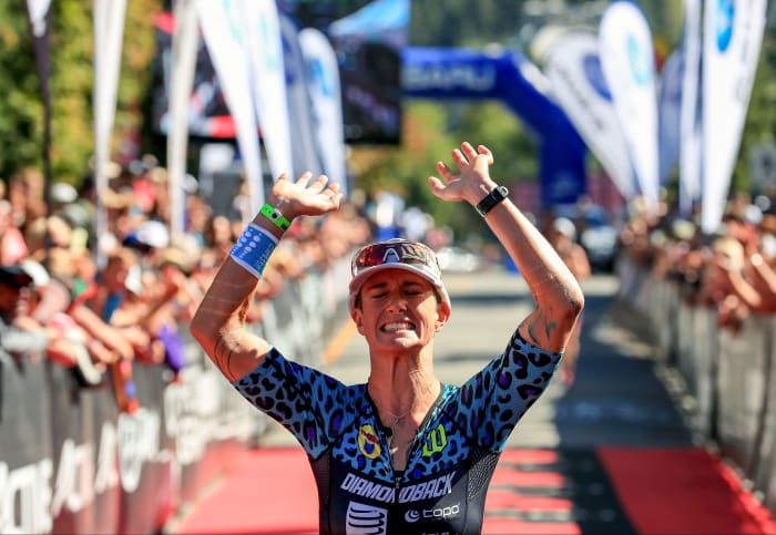 Rach McBride throws her hands up in celebration as she crosses a finish line